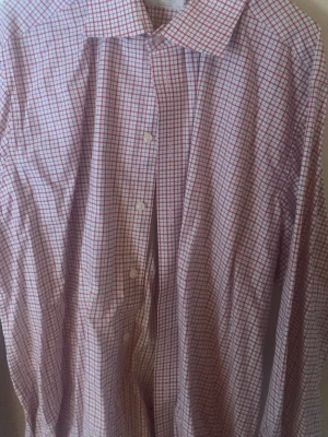 Rutig skjorta från Eton i bomull - Säljer en klassisk rutig skjorta från Eton i storlek 45/17¾. Skjortan har ett mönster med röda och blå rutor på vit botten, långärmad och med knappar framtill. Perfekt för dig som gillar stilrena och tidlösa plagg. Materialet är mjuk bomull.