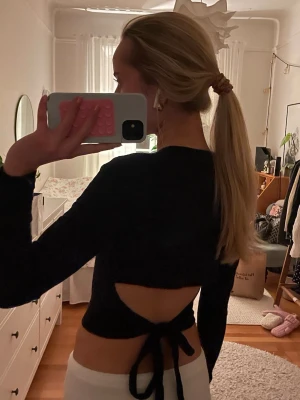 Svart långärmad topp med öppen rygg - Säljer en svart långärmad topp med tight passform. Toppen har en snygg öppen rygg med knytband nedtill. Mycket bra skick, inga tecken på användning. Storlek xs.