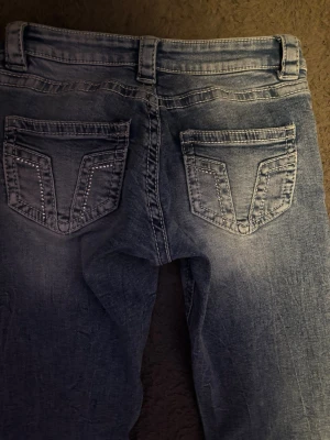 Blå bootcut jeans från Gina Tricot - Snygga blå bootcut jeans från Gina Tricot med ljus tvätt och dekorativa detaljer på bakfickorna. Jeansen har normal passform🤗