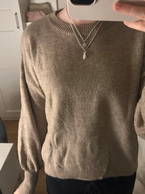 Beige stickad tröja  - Säljer en beige stickad tröja med rund hals och långa ärmar. Tröjan har ribbade muddar vid ärmslut och nederkant. Tröjan är lite nopprig 