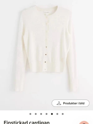 Vit kofta från Holly & Whyte - Säljer en stilren vit kofta från Holly & Whyte by Lindex i storlek XS. Koftan är finstickad med rund hals och har snygga guldiga knappar framtill. Långärmad och med ribbade muddar vid hals och ärmslut. Perfekt att slänga över en topp när det blir lite kyligt.