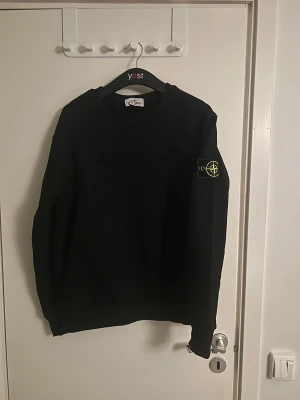 Svart sweatshirt från Stone Island - Säljer en svart Stone Island sweatshirt i mycket gott skick. Klassisk och stilren modell med det ikoniska Stone Island-emblemet på ärmen. En perfekt tröja som funkar lika bra till vardags som till en mer uppklädd look. 	•	Märke: Stone Island 	•	Färg: Svart 	•	Storlek: M 	•	Passform: [t.ex. Regular fit] 	•	Skick: Mycket gott skick 	•	100 % original  Nypris hög – passar dig som vill ha kvalitet, komfort och stil i ett. Hör av dig vid frågor eller för fler bilder! 