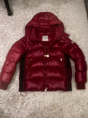 Vinröd Moncler pufferjacka med huva - Säljer denna skit feta vinröda moncler jackan då den börjar bli liten på mig, den är i väldigt bra skick med få slitningar (kom privat för bilder). Tags kommer med och såklart funkar nfc scanner också. Pris kan diskuteras, kom privat för fler bilder!!! PS. kan bara frakta efter 19 december 