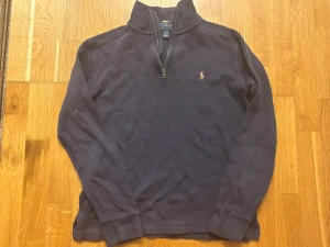 Mörkblå half zip tröja Polo Ralph Lauren - Snygg mörkblå långärmad tröja från Polo Ralph Lauren med klassisk broderad logga på bröstet. Tröjan har en half zip-dragkedja vid halsen och är tillverkad i mjuk bomull. Perfekt för dig som gillar stilrena och tidlösa plagg. Vanligt pris: 1200 kronor, mitt pris: 474. Pris kan diskuteras, skriv om du har frågor.