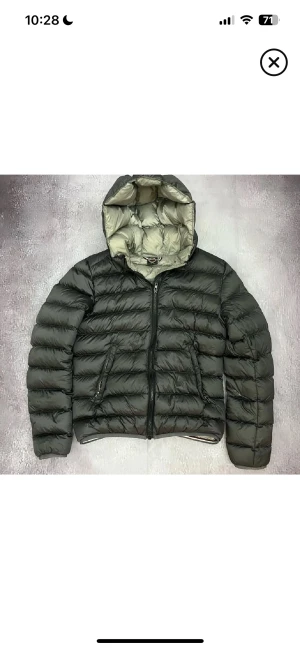 Mörkgrå colmar jacka - Säljer min mörk gråa colmar jacka med huva och dragkedja framtill. Jackan har en liten defekt på ena ärmen, som finns på bild. dragkedjan på ena fickan fungerar ej och går inte att stänga. Perfekt för kalla dagar.