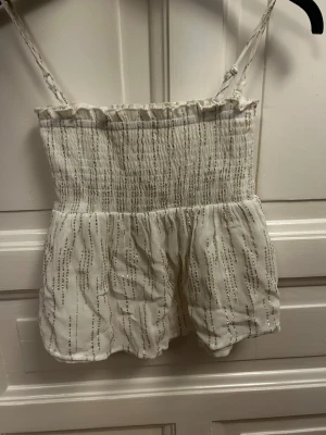 Topp/kjol från Gina Young  - Supersöt vitglittrig linne och kjol (man kan ta av axelbanden) från Gina Tricot. Toppen har smock upptill och volangkant längs överdelen. Perfekt för sommaren, skriv ifall ni vill se fler bilder🫶