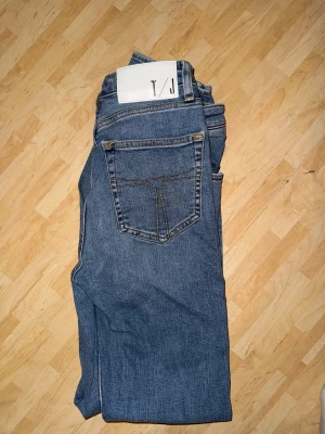 Blå jeans från Tiger of Sweden med raka ben - Snygga blå jeans från tiger of Sweden med klassisk femficksdesign och raka ben. Jeansen har kontrastsömmar och en vit patch med T/J-logga bak i midjan. Materialet är slitstarkt denim och passformen är normal, perfekt för en chill och stilren look.