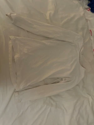 Vit långärmad topp från Cubus - En enkel och stilren vit långärmad topp från Cubus i storlek XS. Modellen är rak med rund halsringning och tillverkad i mjuk bomull. Perfekt att matcha med jeans eller kjol för en clean look.