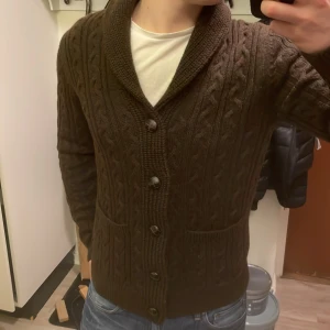 Brun stickad cardigan - Otroligt fet brun stickad cardigan med mönster. Perfekt nu till kallare väder. Modellen är 180cm, 74kg. Priset går såklart att diskuteras!