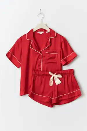 Snygga röda pyjamasshorts i silkesliknande material med vita kontrastsömmar och en bred vit rosett framtill. Shortsen har elastisk midja och avslappnad passform, perfekta för chillkvällar hemma. Tröjan är röd med vita detaljer och röda knappar. I storlek 170 från young gina, köptes förra året.