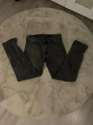 Levi's 511 grå jeans W29 L30 plus bälte Jack and Jones  - Snygga grå jeans från Levi's modell 511 med klassisk femficksdesign och smal passform. Jeansen har en cool tvättad look, svarta sömmar och Levi's ikoniska läderpatch bak i midjan. Perfekt för dig som gillar stilrena och tidlösa jeans.