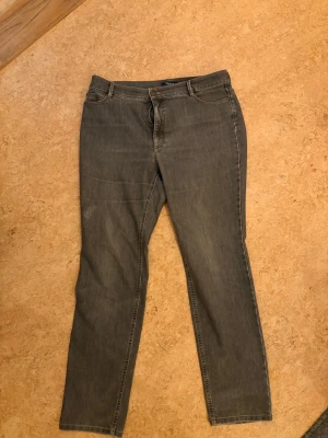 Grå straight jeans från atlier  - Säljer ett par grå jeans från atlier med klassisk femficksdesign och raka ben. Jeansen har subtila slitningar och broderade bakfickor. Perfekta för dig som gillar en enkel och clean look. Materialet är mjukt och följsamt jeans. notera slitning 