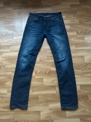 Jack & Jones Jeans - Säljer ett par Jack & Jones jeans i marinblått, W30/L34. Regular/Clark fit som sitter bekvämt och passar till allt. Använda men i bra skick utan några större märken eller slitage. Perfekta basjeansen för vardag.