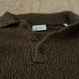 Olive grön stickad pikétröja Les Deux - Säljer en brun stickad pikétröja från Les Deux med grov struktur. Tröjan har klassisk krage, knappar vid halsen och lång ärm. Broderad Les Deux-logga nertill. Perfekt för dig som gillar en chill och stilren look.ordinare pris 1200! Har används 6-7 gånger 🙃