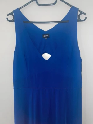 Blå långklänning med v-ringning - Snygg blå maxi långklänning från Bubbleroom med v-ringad hals och lite halvöppen rygg. Klänningen är ärmlös och har en mjuk, följsam passform som ger en skön känsla. Perfekt för dig som gillar stilrena och enkla plagg med en twist.