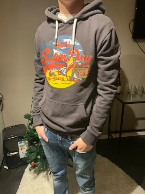 Superdry hoodie med ett snyggt tryck - Säljer denna stilrena feta Superdry hoodien med ett super snyggt tryck, tröjan har en tvättad look och ger vibbar av en chill outfit men det ser ändå inte dåligt ut. Skriv om du har frågor eller funderingar‼️
