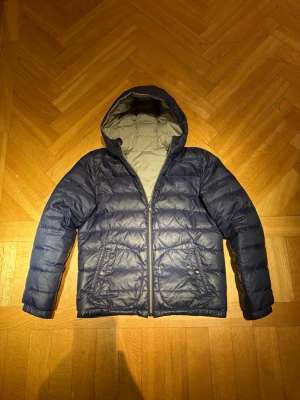 Marinblå och grå Dunjacka Polo Ralph Lauren - Säljer en vändbar dunjacka  från Polo Ralph Lauren i grå och marinblå. Perfekt för dig som vill ha en varm och snygg jacka på både vintern våren och hösten. Eftersom jackan är vändbar så står ingen storlek men skulle säga att den passar från 155-168 då jag är 168. Skriv om ni har några frågor. Mvh Victor