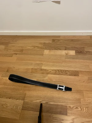 H bälte  - Bilderna visar ett svart bälte med silvrigt H-spänne, men ingen väst finns med. Kan därför inte ge någon beskrivning eller taxonomi för väst.