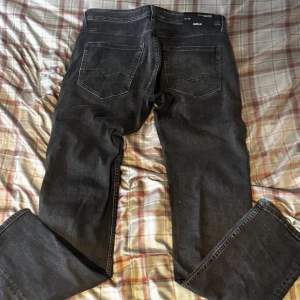 Replay svarta jeans straight fit - Svarta jeans från Replay med klassisk femficksdesign och raka ben. Jeansen har diskreta slitningar och mörk tvätt, samt tydliga sömmar på bakfickorna. Materialet är jeans med en mjuk känsla och passformen är normal.