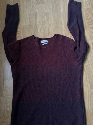 Vinröd stickad tröja Jack & Jones - Säljer en vinröd stickad tröja från Jack & Jones Originals i storlek small. Tröjan har rund hals och långa ärmar, med en mörkare ton mot ärmarna. Perfekt för dig som gillar enkel och stilren design med lite extra färg.