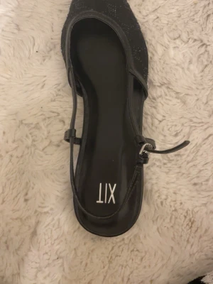 Svarta ballerinaskor med spetsig tå från XIT - Säljer ett par svarta ballerinaskor från XIT i storlek 40. Skorna har spetsig tå, låg klack och snygga glittriga detaljer på ovansidan. Aldrig använda