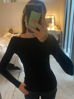 Svart långärmad topp H&M - Säljer en svart, långärmad topp med avklippt offshoulder-skärning som liknar intimissimi toppen! Den är tight, mjuk och är tillverkad i ett stretchigt material som sitter snyggt på kroppen. Perfekt både klä upp och ner! 