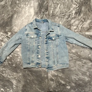 Ljusblå jeansjacka från &Denim - Snygg ljusblå jeansjacka från &Denim med klassisk krage, knappar framtill och två bröstfickor med lock. Jackan har långa ärmar och är tillverkad i denim med en schysst tvättad look. Perfekt för dig som gillar en avslappnad och trendig stil.