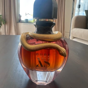 Pure XS Eau de Parfum 50ml - Snygg parfymflaska från Paco Rabanne, Pure XS For Her. Flaskan är djupt röd med en cool guldig orm som slingrar sig runt halsen och har svart kork. Glasflaskan har en lyxig och unik design som verkligen sticker ut i samlingen. Ungefär 40ml kvar. 
