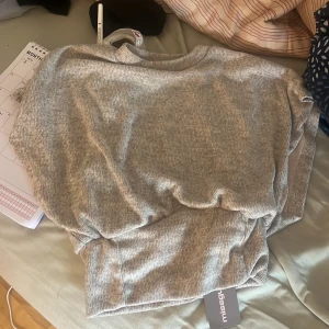 Grå/beige stickad tröja från Missguided - Mysig grå stickad tröja från Missguided i storlek S. Tröjan har en enkel design med rund halsringning och ribbade muddar vid ärmslut och nederkant. Perfekt för lager-på-lager under kyliga dagar.