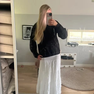 Vit långkjol med volangdetaljer - Säljer en flowy vit långkjol med flera volangliknande sömmar. Kjolen har en enkel och clean look, perfekt för dig som gillar en chill och stilren vibe. Resår i midjan för skön passform. Passar till sneakers eller sandaler.