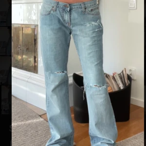 ljusblå bootcut jeans - Ljusblå jeans från Dallas Jeans med bootcut passform och låg midja. Jeansen har slitna detaljer och hål vid knäna. Storlek W30 (midjemått runt 76cm) L32 (innerbenslängd 38cm) jag är 167 cm❤️