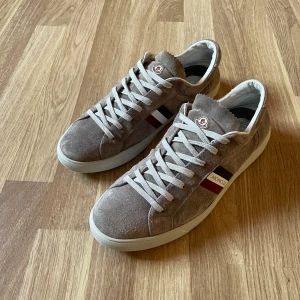 Moncler skor i grå mocka  - Ett par gråa moncler skor i mocka med storlek 44. Skorna är i bra skick , men slitna på vissa ställen. Original kartong finns inte. 