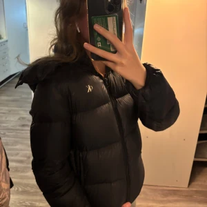 Svart dunjacka från Calvin Klein - Säljer en svart dunjacka från Calvin Klein med puffig look och dragkedja framtill. Jackans har tappat lite luft