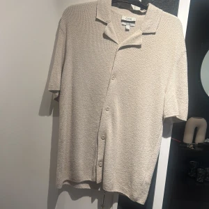 Beige kortärmad skjorta från COS - Säljer en beige kortärmad skjorta från COS med avslappnad passform. Som ny och sparsamt använd