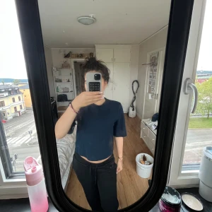 Mörkblå croppad topp från Nelly - En enkel och stilren mörkblå croppad topp från Nelly. Toppen har korta ärmar och rund halsringning, perfekt för en chill och avslappnad look. Materialet känns mjukt och lätt mot huden.