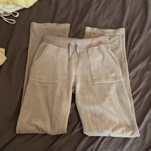 Beige juicy byxor - Säljer ett par beige juicys i mjukt material. Byxorna har fickor fram, och bakfickor med lock och knappar. Perfekta för chill dagar och har en loose passform. De har en pytte pytte liten fläck som inte går bort, som man ser på tredje bilden men den syns ej