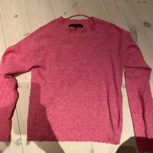 Rosa stickad tröja från Vero Moda - Mysig rosa stickad tröja från Vero Moda i storlek S. Tröjan har en rund halsringning, ribbade muddar och långärmade ärmar. Perfekt för att hålla dig varm och snygg under kyliga dagar. Enkel och stilren design som är lätt att matcha med dina favoritjeans.