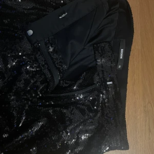 Svart paljettkjol från Bikbok - Glittrig svart byxor från Bikbok, täckt med paljetter som ger en riktigt snygg och festlig look. Använd endast. 