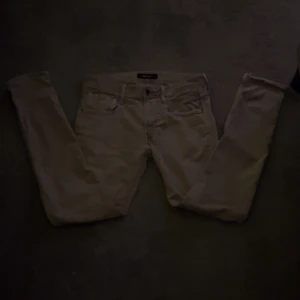 Replay anbass - Säljer ett par snygga gråa jeans i slim fit med klassisk femficksdesign. Byxorna har normal midja och raka ben, perfekta för en clean och stilren look. Tillverkade i mjuk bomull med lite stretch för extra komfort.