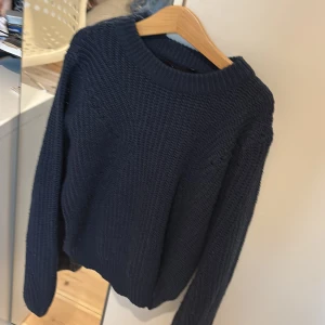 Mörkblå stickad tröja XOXO friends - Mysig mörkblå stickad tröja från XOXO friends med grov ribbstickad struktur och rund hals. Perfekt för lager-på-lager och chill dagar. Långärmad och enkel att matcha med jeans eller kjol.