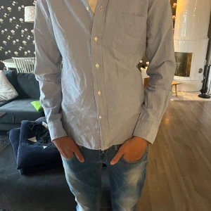 Ljusblå bomullsskjorta med knappar - Snygg ljusblå skjorta i bomull med klassisk krage och mycket bra skick. Hör bara av er om ni har någon fråga!