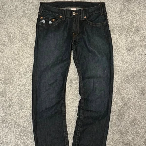 True Religion Jeans Herr - Säkjer dessa super snygga True Religion Jeans med en loose/rak fit eftersom de blivit för korta för mig. Har en snygg wash och snygg slitning på broderingen på bakfickorna. Annars är de som nya! Hör av dig vid frågor! :)