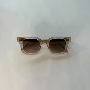 Transparenta CHIMI solglasögon - Snygga solglasögon från CHIMI med transparent, fyrkantig båge och bruna tonade glas. Riktigt clean design med coola detaljer på skalmarna och CHIMI-logga. Kommer med originalfodral. Perfekta för dig som vill sticka ut med stilren vibe.