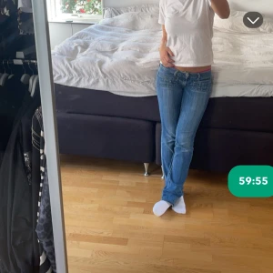Lågmidjade blå jeans med bootcut - Säljer ett par blå jeans med låg midja och bootcut-snitt. Jeansen har klassisk femficksdesign och snygga slitningar framtill. Perfekta för dig som gillar en avslappnad och trendig look. Passar till allt och är riktigt sköna på.