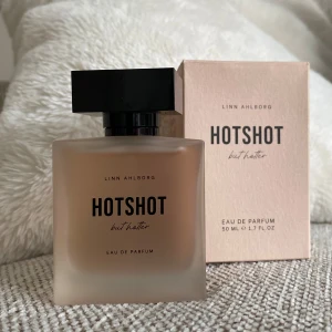 Hotshot by Linn Ahlborg parfym - Linn Ahlborgs trendiga parfym ”Hotshot but hotter” är en varm och stilren doft samtidigt som den är elegant och exklusiv på personen som bär den. De lekfulla toppnoterna av svartvinbär, bergamott och mandarin kombineras perfekt ihop med noter från hallon, neroli och jasmin. I basen finns vanilj och mysk som ger doften dess eleganta ton.  Köptes för 600 kr endast testad kartongen finns kvar 