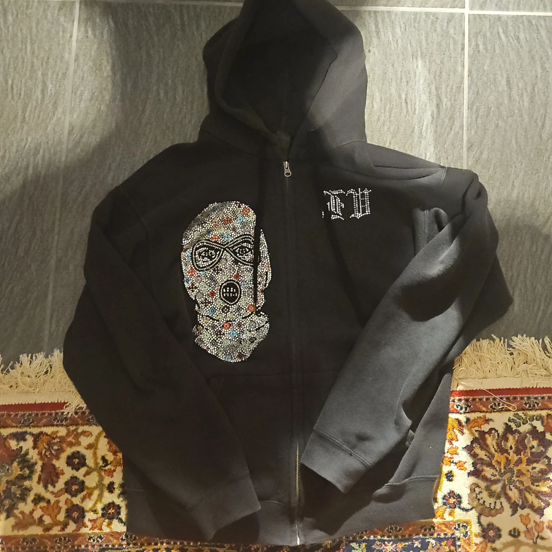 Svart hoodie med strassmask och text
