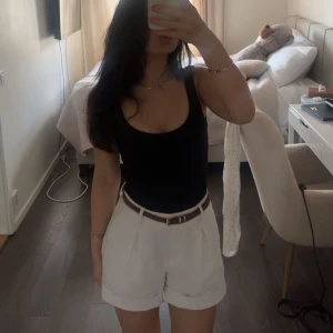 Vita högmidjade shorts med veck - Snygga vita shorts med hög midja och breda uppvikta benslut. De har stilrena veck framtill som ger en cool och dressad vibe. Perfekta för sommarens alla häng och passar till både t-shirt och skjorta. Materialet känns lätt och luftigt.