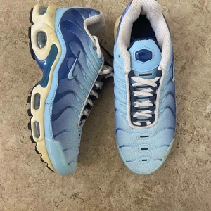 Nike Air Max Plus blå sneakers - Nike Air Max Plus sneakers i olika blå nyanser med vita och mörkblå detaljer. Skorna har mesh- och syntetmaterial, synliga Air Max-bubblor i sulan och klassisk snörning. Snygg vågig design på ovandelen och vit innersula för extra komfort.
