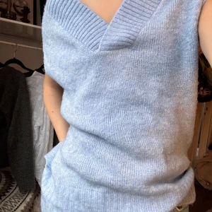 Ljusblå stickad väst med v-ringning - Supermysig ljusblå stickad väst  med bred ribbad v-ringning . 