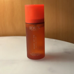 IDUN Minerals Ready Set Fix Setting Spray - Setting spray från IDUN Minerals i en snygg orange plastflaska med matchande lock. Ready Set Fix ger en naturlig glow och håller sminket på plats hela dagen. Perfekt för dig som vill ha ett fräscht och hållbart resultat.